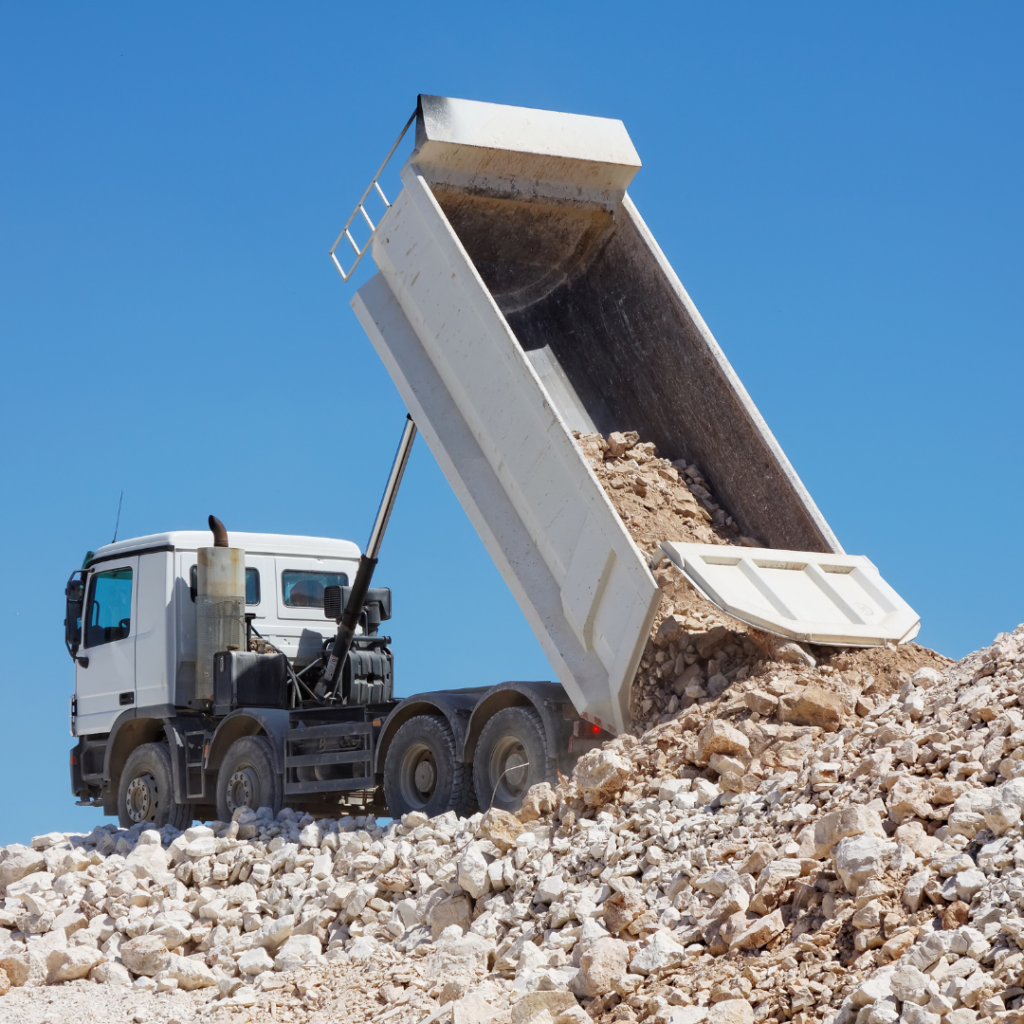 Kamion që shkarkon çakëll gjatë procesit të transportit të mallrave ndërtimore në Shqipëri